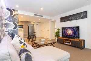 a living room with a couch and a tv at Inner city 1 bedroom Apartment with Rooftop pool and Parking - Serain Residences in Brisbane