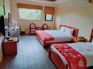 una camera d'albergo con due letti e una televisione di Old House Homestay a Sanxing