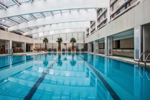 een groot zwembad met blauw water in een gebouw bij Beijing Hotel in Beijing