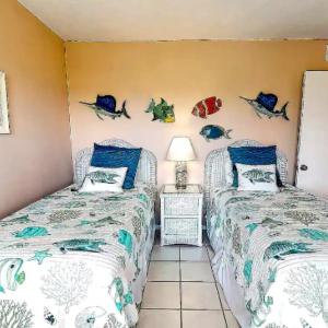 two beds in a room with fish on the wall at Sarasota Pool Apartment in Siesta Key