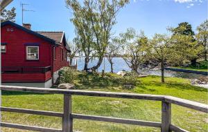 a red house with a fence next to a body of water at Beautiful Home In Oskarshamn With Wifi And 2 Bedrooms in Oskarshamn