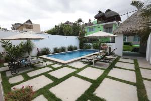 a backyard with a swimming pool and two chairs and umbrellas at Hotel Suites Del Mar in La Manzanilla