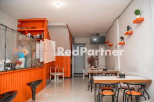 a restaurant with orange and white walls and tables at Hotel C18 at Cibaduyut Mitra RedDoorz in Bandung