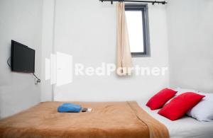 萬隆的住宿－Hotel C18 at Cibaduyut Mitra RedDoorz，一间卧室配有一张带红色枕头的床和电视。