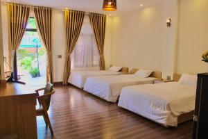 a hotel room with two beds and a window at The Cau Garden House in Ấp Long Hồ Hạ