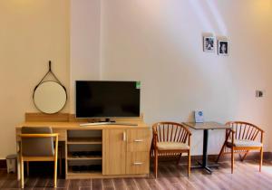 a living room with a tv and a table with chairs at The Cau Garden House in Ấp Long Hồ Hạ