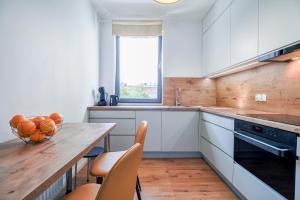 a kitchen with white cabinets and a wooden table at CITYSTAY Garden Gates Apartment in Gdańsk