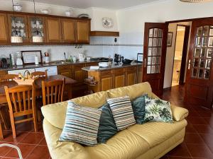 COZY APARTMENT ERICEIRA WITH SEA VIEW في إيريسييرا: غرفة معيشة مع أريكة ومطبخ