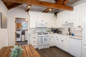 a white kitchen with white appliances and a wooden table at Bayview Bungalow - Cabin with Hot Tub One Block from Big Bear Lake! in Big Bear Lake