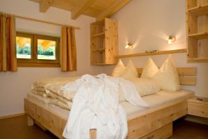 1 dormitorio con 1 cama con sábanas y almohadas blancas en Haus Sonnberg, en Kals am Großglockner