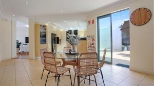 a dining room with a table and chairs and a clock at Market Street Penthouse in Merimbula