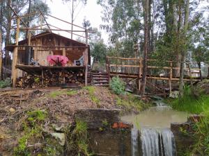 a wooden house with a waterfall and a bridge at La chala Guatavita in Guatavita