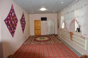 um quarto com tapete vermelho e papagaios na parede em Khiva Mirza Bobur Guest House em Khiva