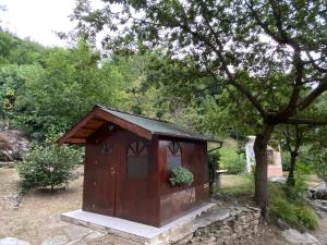 una piccola casa di legno per cani, seduta accanto a un albero di LA CASA DEI NONNI con SPA privata su richiesta a Pont Canavese