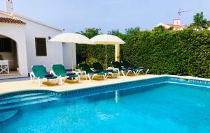a swimming pool with lawn chairs and umbrellas next to a pool at Villa Leon Menorca, tu casa menorquina! in Cala'n Bosch