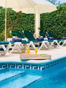 una piscina con sillas y sombrillas junto a una piscina en Villa Leon Menorca, tu casa menorquina!, en Cala'n Bosch