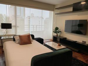 een woonkamer met een bed en een flatscreen-tv bij MLA apartments - Alcanfores in Lima