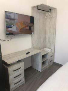 a desk with a mirror and a tv on a wall at Sunset Luxury Studios in Radhimë