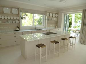a white kitchen with a large counter and stools at Villa Mimi Beachfront Beau Vallon in Beau Vallon