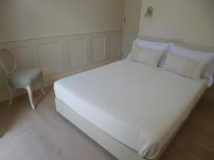 a white bed with pillows and a chair in a room at Villa Mimi Beachfront Beau Vallon in Beau Vallon +11 photos
