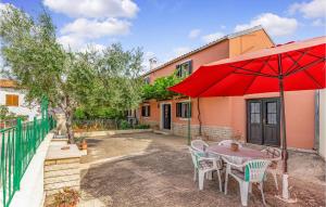 a patio with a table with a red umbrella at Nice Home In Medulin With Kitchen in Medulin