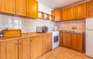 a kitchen with wooden cabinets and white appliances at Nice Home In Medulin With Kitchen in Medulin