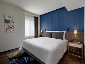 a bedroom with a large white bed and a blue wall at Sindhorn Midtown Hotel Bangkok, Vignette Collection by IHG in Bangkok