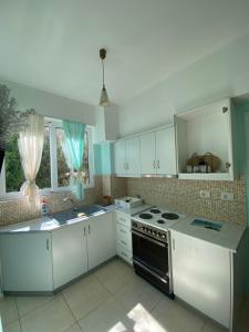 a kitchen with white cabinets and a stove top oven at Villa Sopebra in Sarandë