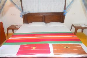 Una cama con una manta de rayas de colores. en Jayanika Residence, en Tangalle