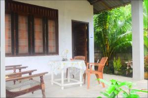 a table and chairs on a porch with a table and benches at Jayanika Residence in Tangalle