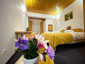 a hotel room with a bed and a vase of flowers at Pensiunea Ursuleț Bran in Bran