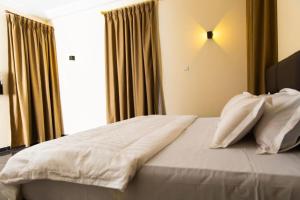 アクラにある1 bedroom Space Available to enjoyの寝室にある白いシーツと枕が置かれたベッド