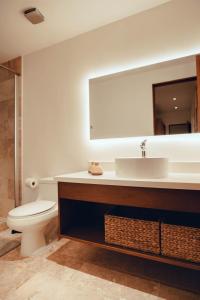 a bathroom with a toilet and a sink and a mirror at Stylish Luxury Condo in the heart of Playa in Playa del Carmen