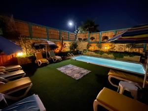 una piscina por la noche con sillas y sombrilla en Halat sailing club Guest house, en Ad Dawwārah