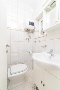 La salle de bains blanche est pourvue de toilettes et d'un lavabo. dans l'établissement Kuća za odmor Tommy, à Trogir