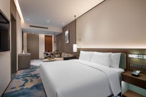a bedroom with a large white bed and a living room at Wanda Jin Xiangjiang Dingzhou in Dingzhou