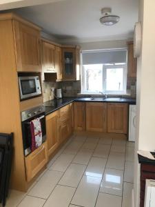 a large kitchen with wooden cabinets and a window at Cheerful 4 bedroom town house with bbq, in Galway