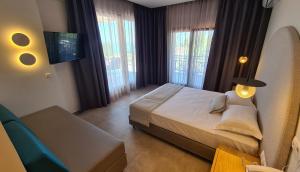 a bedroom with a bed and a couch and windows at Palladium Hotel in Kriopigi