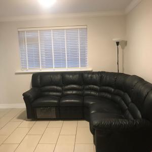a black leather couch in a living room with a window at Cheerful 4 bedroom town house with bbq, in Galway