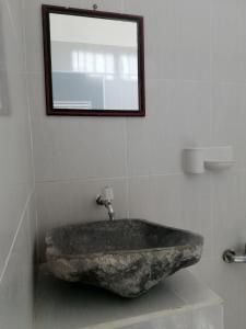 a stone sink in a bathroom with a mirror at Vacation Inn Gili in Gili Trawangan +3 photos