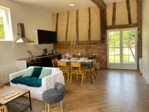 een woonkamer met een keuken en een tafel met stoelen bij La petite ferme de Roumare in Roumare