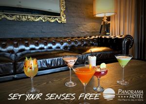 four cocktails on a table in front of a leather couch at Panorama Hotel - Free EV Charging Station in Varna City