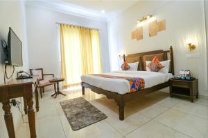 um quarto com uma cama, uma secretária e uma televisão em FabHotel K9 Villa em Ludhiana