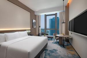 une chambre d'hôtel avec un lit et une télévision dans l'établissement Wanda Jin Xiangjiang Dingzhou, à Dingzhou