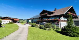 a house with flowers on the side of a road at Ferienwohnungen Britta Heim in Oberstaufen