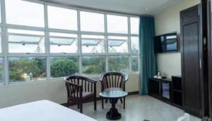 a bedroom with two chairs and a table in front of a window at Mbale Courts View Hotel in Mbale