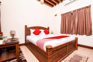 Capital O160 Lumbini Dream Garden Guest House LLC في دبي: غرفة نوم مع سرير مع وسائد حمراء ومكتب