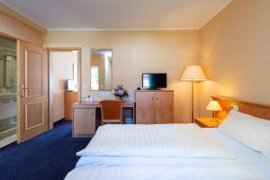 a hotel room with a bed and a desk and a television at Waldhotel Humboldtsee in Salzhemmendorf +27 photos