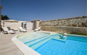 une piscine avec des chaises et un mur en pierre dans l'établissement Beautiful Home In Ragusa With House Sea View, à Raguse