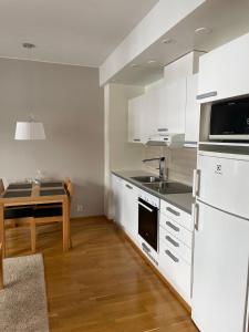 une cuisine avec des placards blancs et une table. dans l'établissement Chalets LumiHelmi, à Ruka